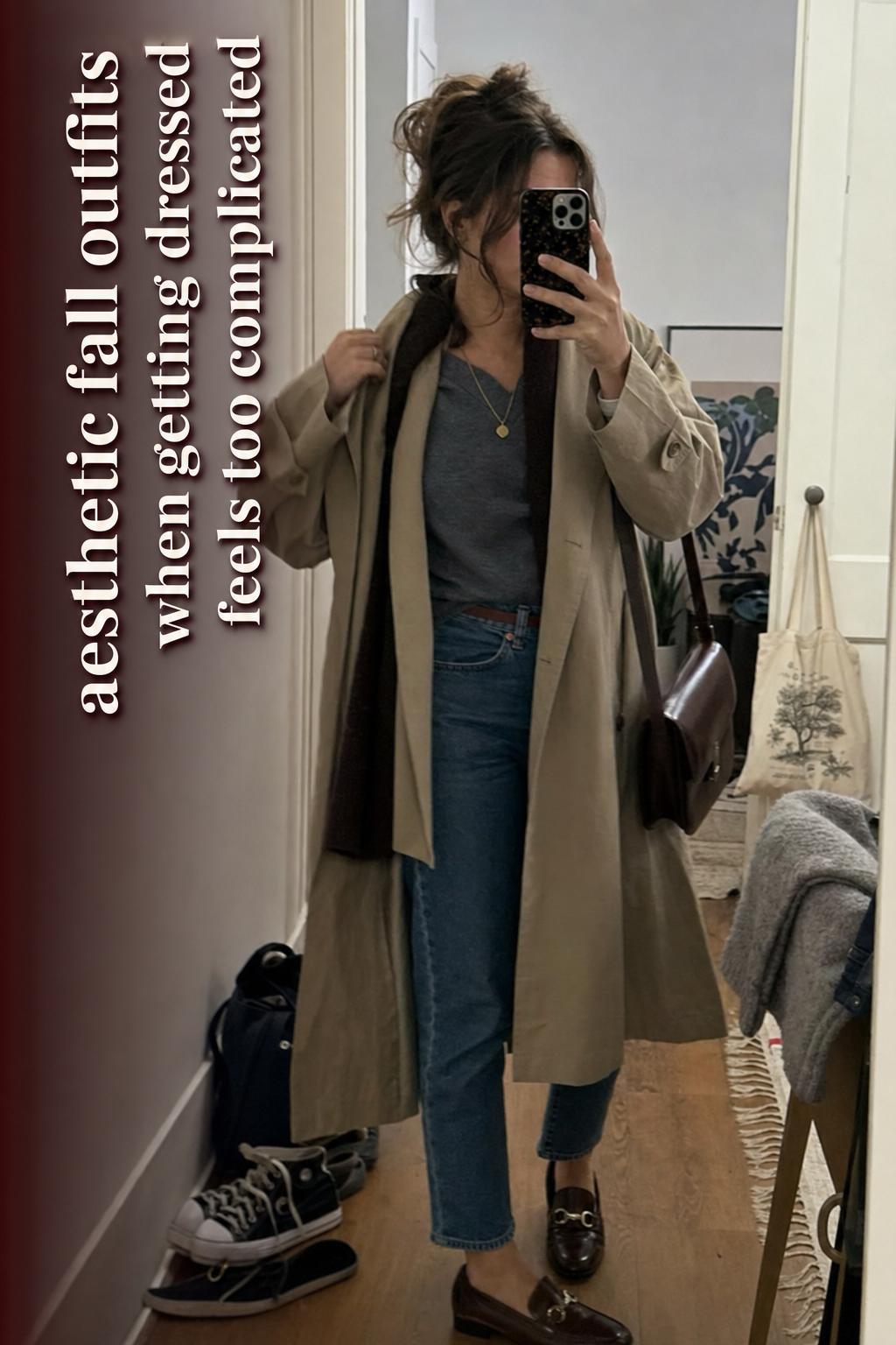 Woman mirror selfie in trench coat and denim showing aesthetic fall outfits in a lived-in apartment hallway