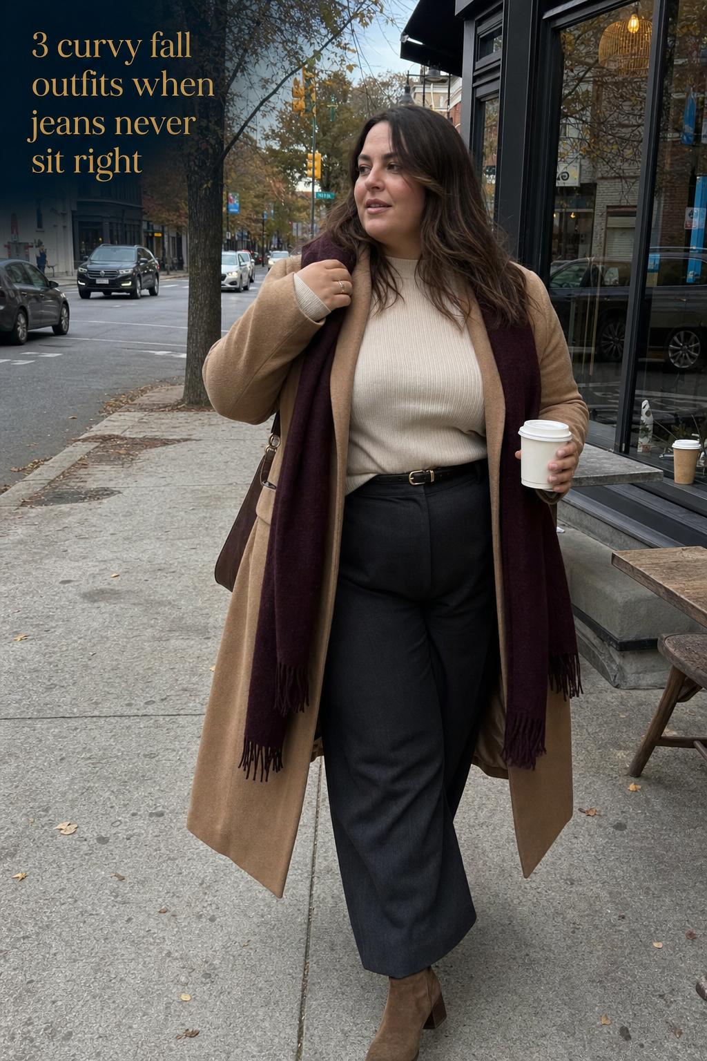 Curvy fall outfits on a plus-size woman walking past a cafe in a camel coat and wide-leg trousers on an overcast day