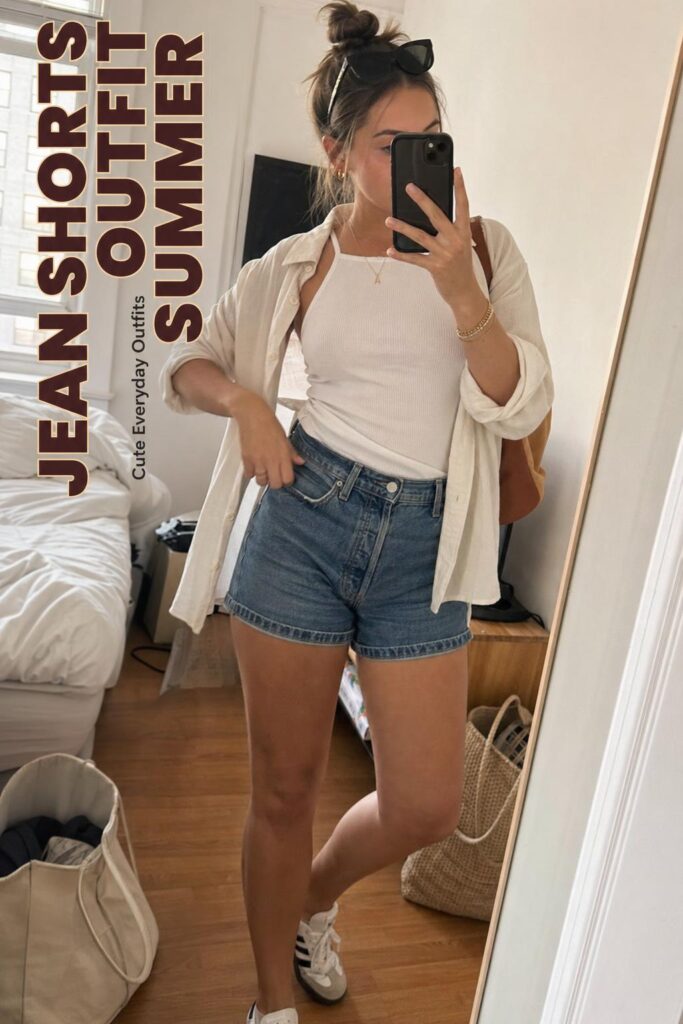 Casual mirror selfie in a lived-in apartment showing a jean shorts outfit summer look with white tee, open linen shirt and sandals