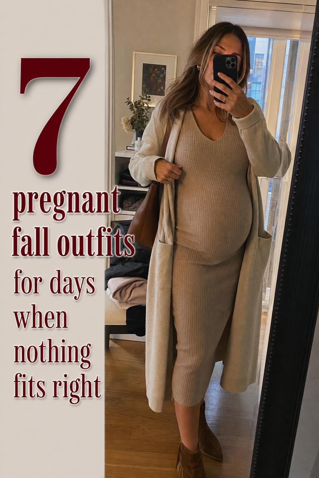 Mirror selfie of early fall maternity style in apartment hallway, featuring pregnant fall outfits with cardigan and knit dress