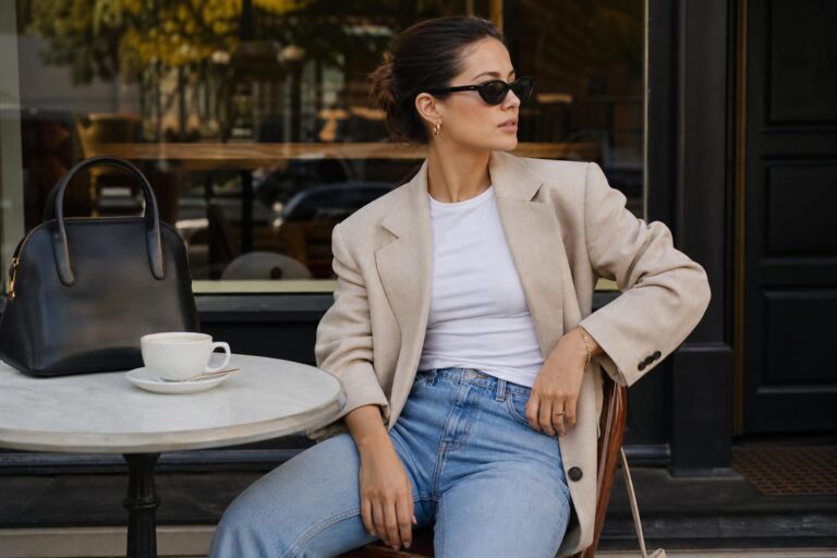 Basic clean girl outfits with white tee, straight blue jeans, black loafers, and a beige blazer in bright natural light