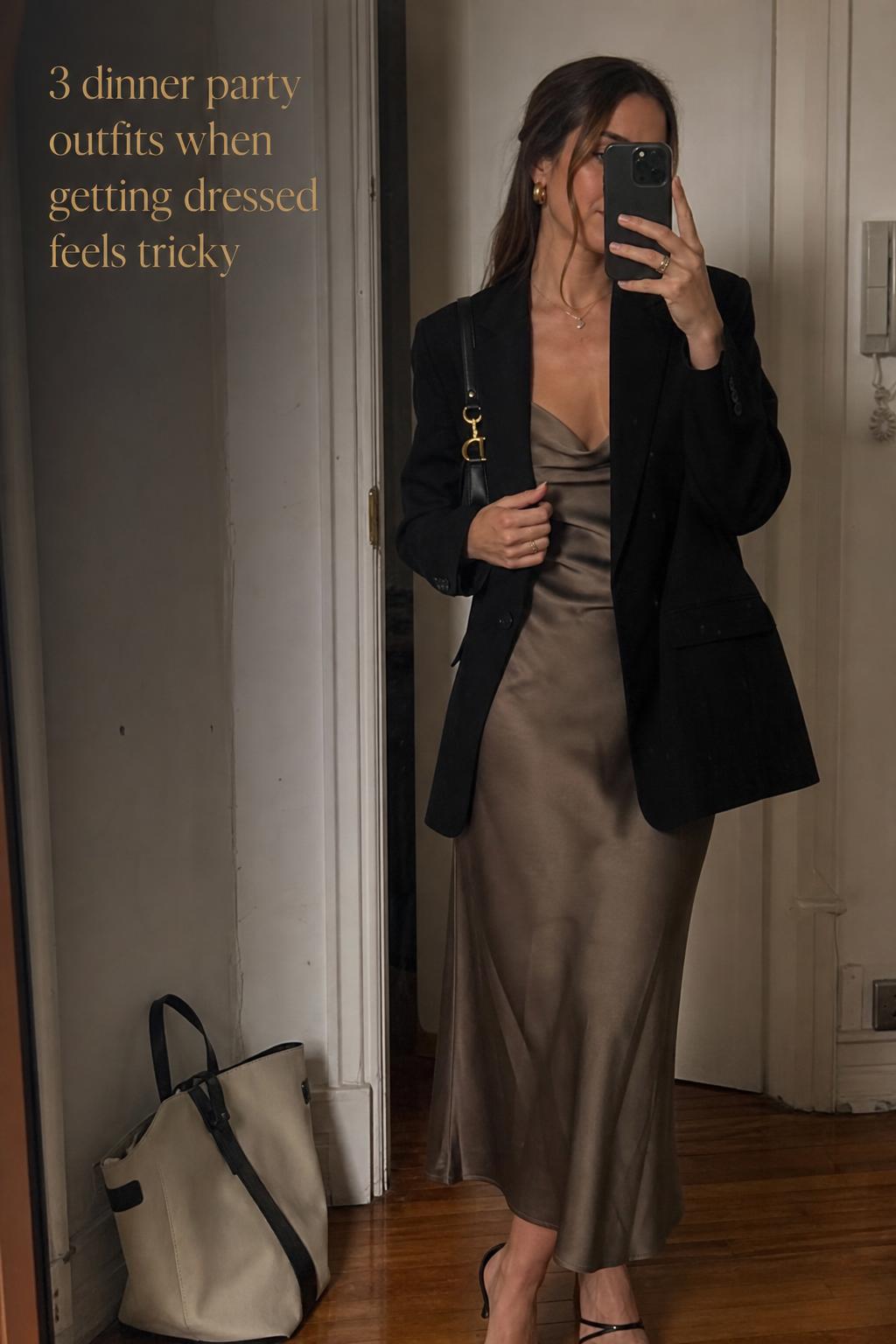 Dinner party outfits mirror selfie in a softly lit apartment hallway, woman in blazer over midi dress with clutch