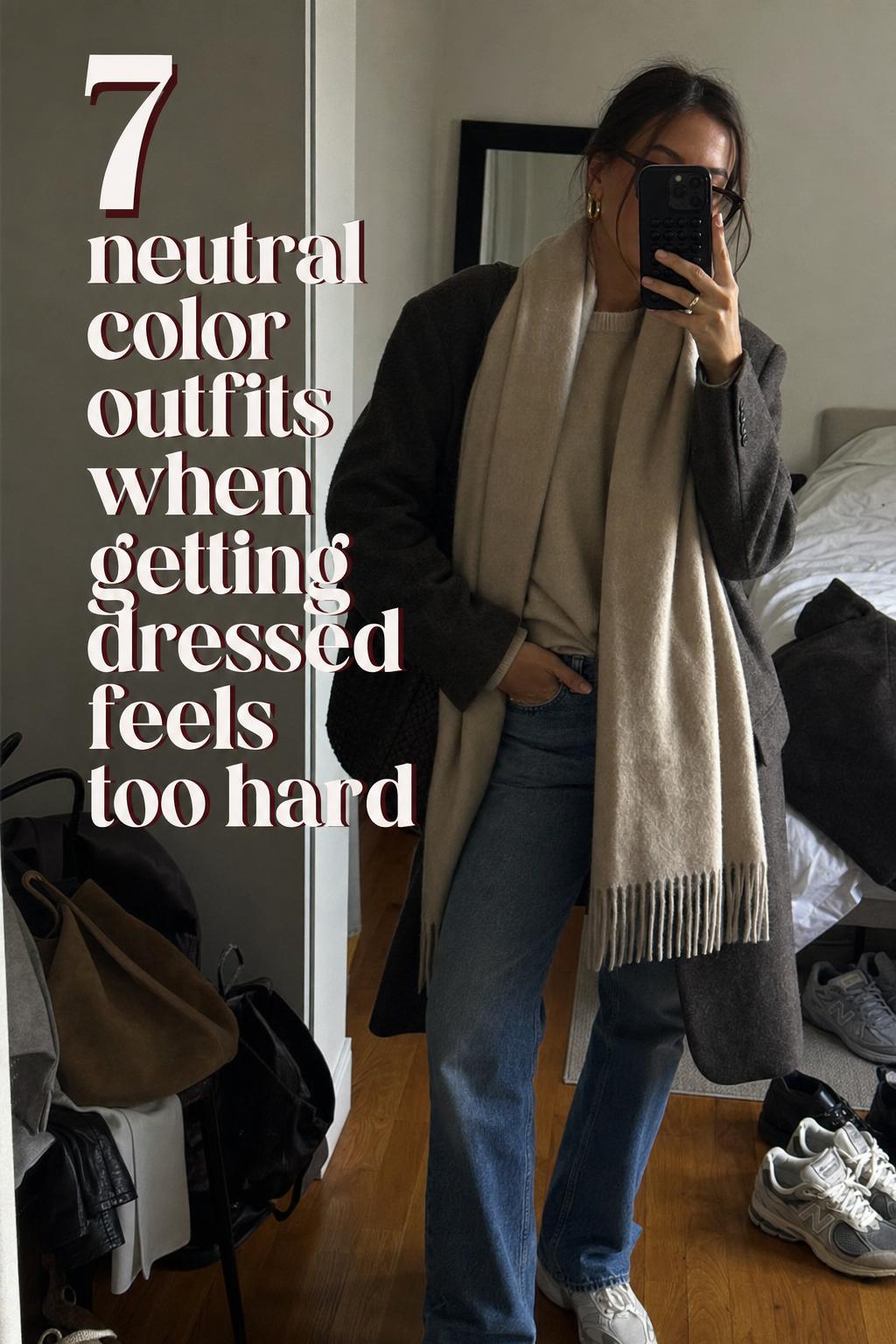 Mirror selfie of a person in timeless neutral color outfits in a lived-in bedroom with casual clutter and window light