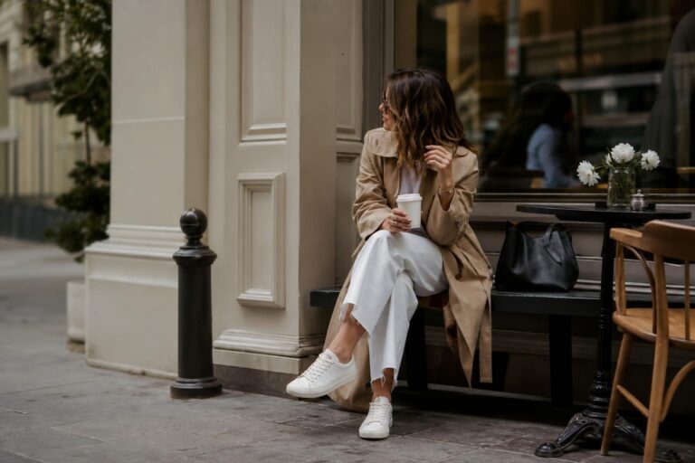 Outfits with white sneakers styled with straight-leg jeans, a neutral blazer, and a leather shoulder bag on a city street