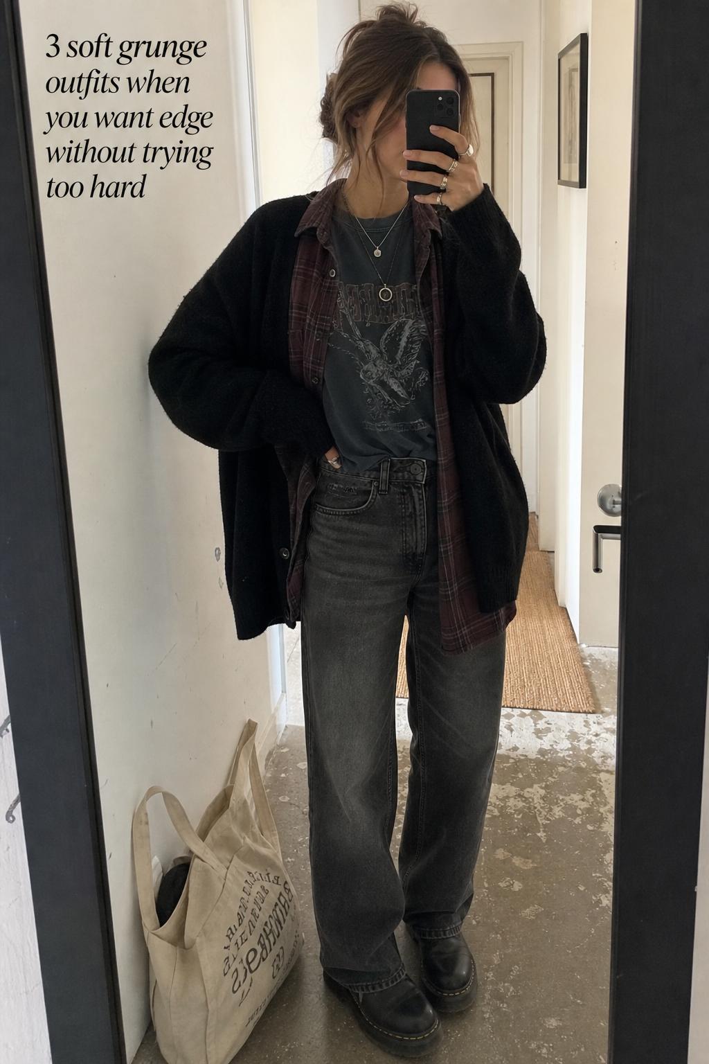 Mirror selfie in an apartment hallway wearing soft grunge outfits with a charcoal tee, plaid flannel, cardigan, and faded denim.